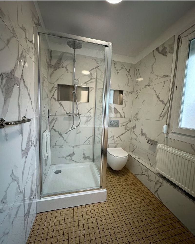Après rénovation : salle d'eau rénovée en marbre avec douche vitrée et WC suspendu