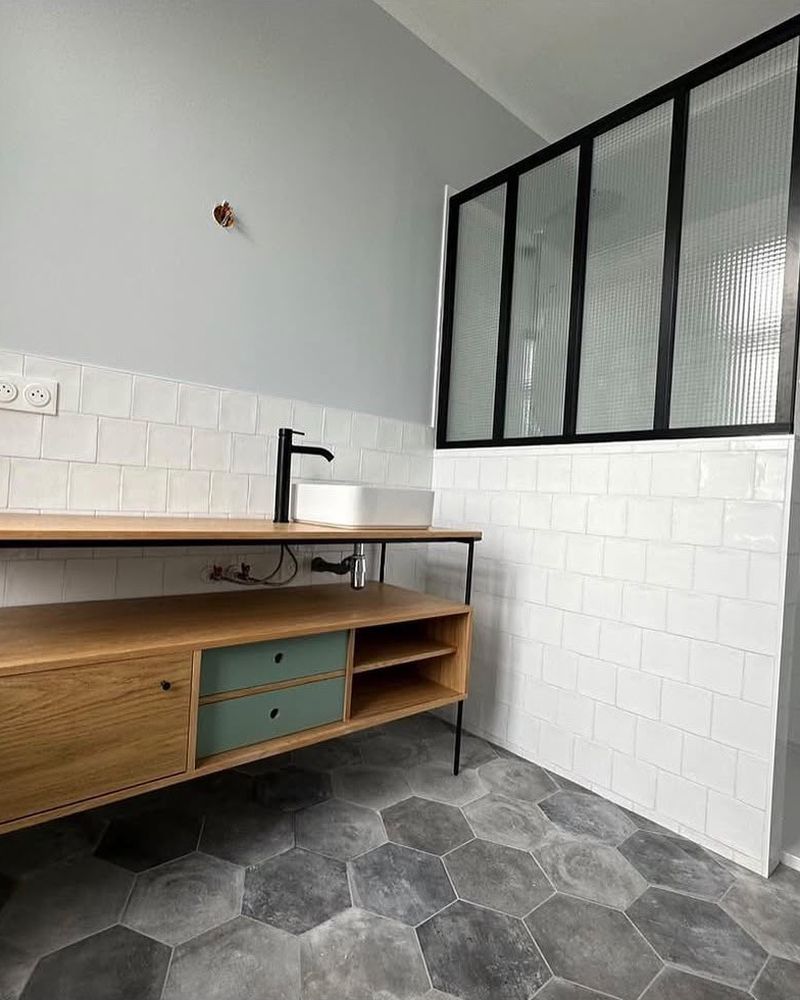 Après rénovation : salle de bain avec meuble en bois, verrière et carrelage hexagonal